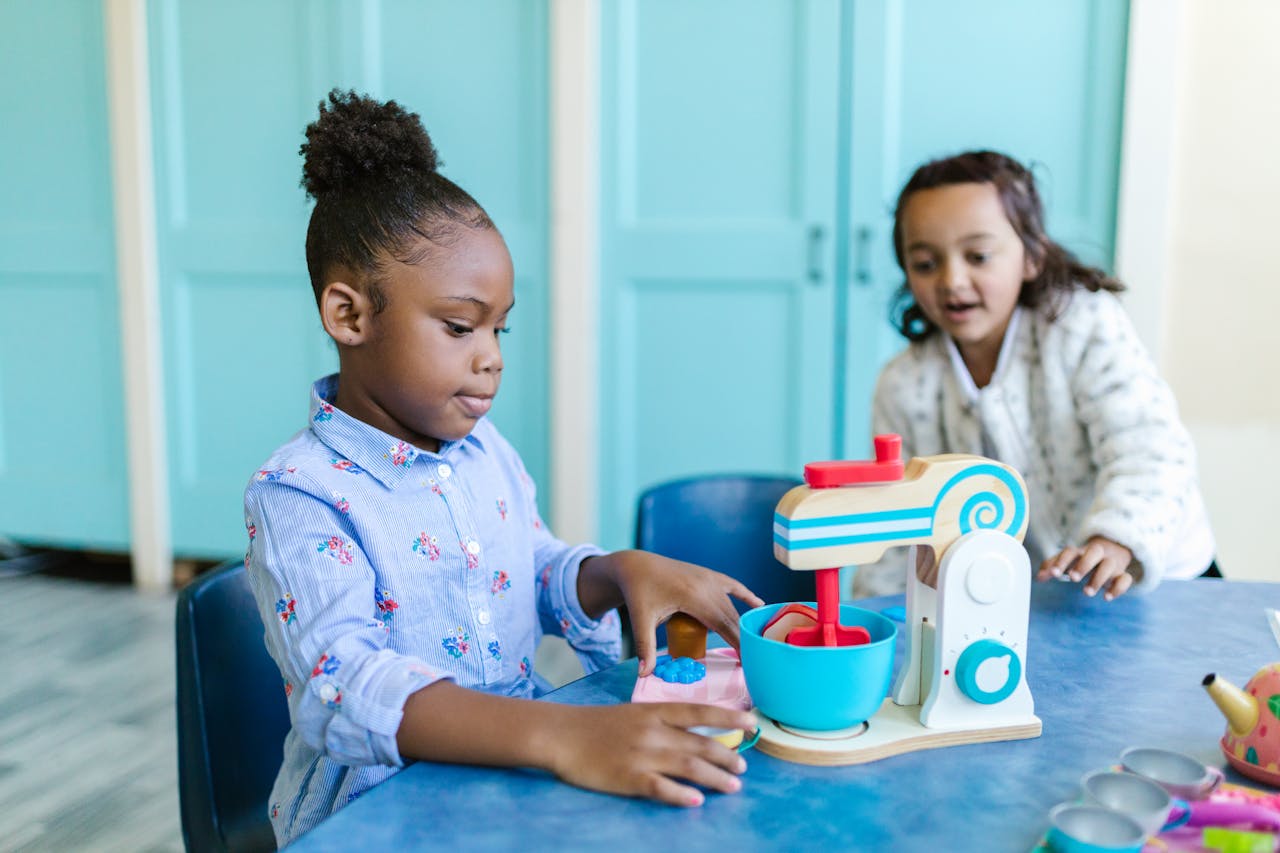 Two children enjoy playing with a toy kitchen set indoors, having fun and learning.